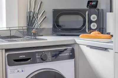 a kitchen with a microwave and a washing machine at Pinkerton House - 3 bed Rutherglen in Glasgow