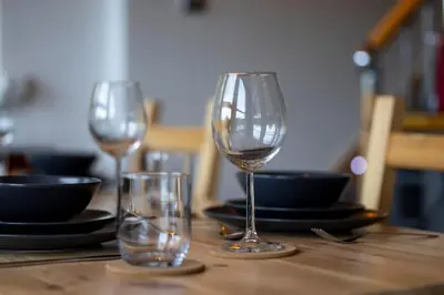 three wine glasses sitting on top of a wooden table at Cosy Lodge Getaway with Private Beach & Fireplace in Erskine