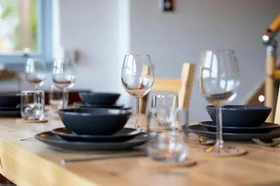 a wooden table with wine glasses and plates on it at Cosy Lodge Getaway with Private Beach & Fireplace in Erskine