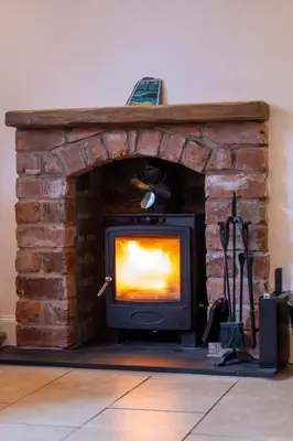 a stone fireplace with a television in it at Cosy Lodge Getaway with Private Beach & Fireplace in Erskine