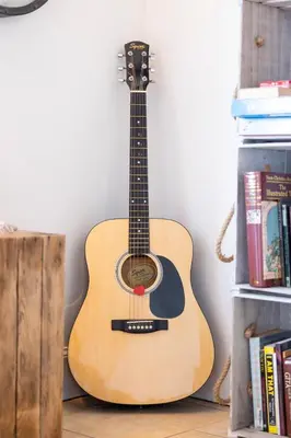 a guitar is leaning against a wall at Cosy Lodge Getaway with Private Beach & Fireplace in Erskine