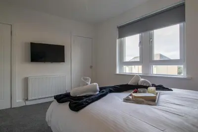 a bedroom with a large white bed with a tv on the wall at The Wishy - 2 Bedroom Flat in Newmains in Newmains