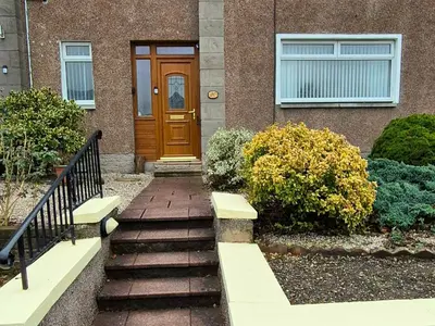a house with a brown door and stairs in front at Stirling apartment - free parking in Stirling