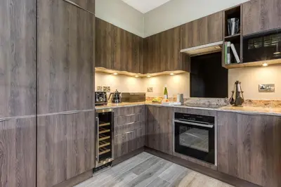 a kitchen with wooden cabinets and a dishwasher at Gate Lodge in Castle Douglas