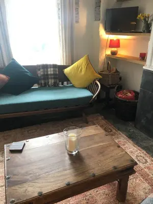 a living room with a couch and a wooden coffee table at Romantic Cottage, Port Isaac in Moffat