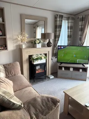 a living room with a couch and a tv and a fireplace at Home from Home at the Hendersons Caravan in Kilwinning
