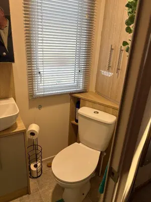 a bathroom with a white toilet and a sink at Home from Home at the Hendersons Caravan in Kilwinning