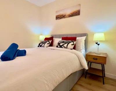 a bedroom with a large white bed with two lamps at Garden-View 2BR Apartment - Free Parking & WiFi in Glasgow