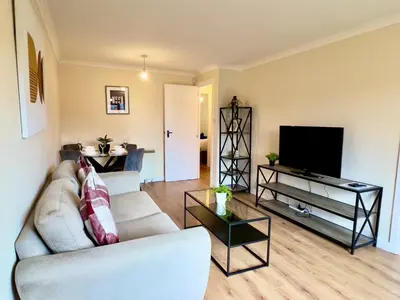 a living room with a couch and a flat screen tv at Garden-View 2BR Apartment - Free Parking & WiFi in Glasgow