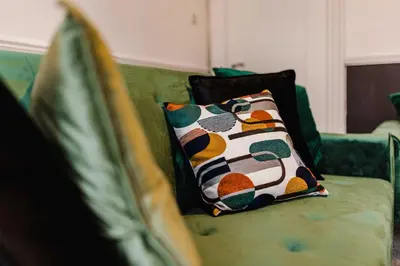 a green couch with a pillow on it at Welcoming Home In Renfrew, Near Glasgow Airport - Bonnie Lodgings in Renfrew