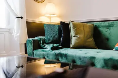 a living room with a green couch with pillows at Welcoming Home In Renfrew, Near Glasgow Airport - Bonnie Lodgings in Renfrew