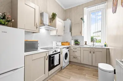 a kitchen with white cabinets and a dishwasher at Welcoming Home In Renfrew, Near Glasgow Airport - Bonnie Lodgings in Renfrew