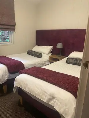 a bedroom with three beds with white and red sheets at Ardeonaig Rock in Morenish
