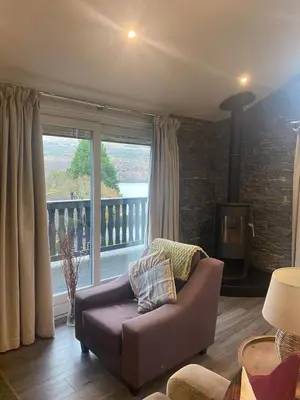 a living room with a couch and a large window at Ardeonaig Rock in Morenish