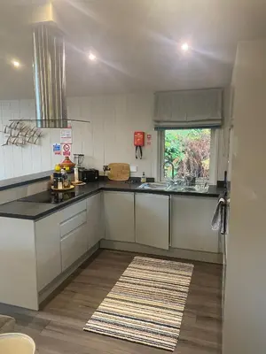 a kitchen with white cabinets and a sink and a window at Ardeonaig Rock in Morenish