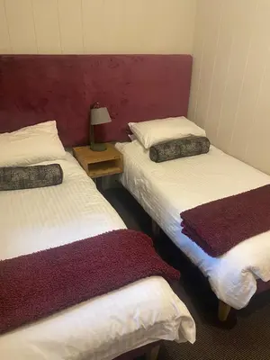 a room with two beds and a table with a lamp at Ardeonaig Rock in Morenish