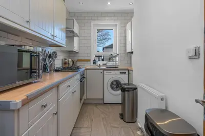 a kitchen with white cabinets and a washer and dryer at Executive 3 Bedroom - Corporate And Contractor Stays in Glasgow