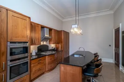 a kitchen with wooden cabinets and a black counter top at Georgian Elegance with Patio Garden West End - Pass the Keys in Edinburgh