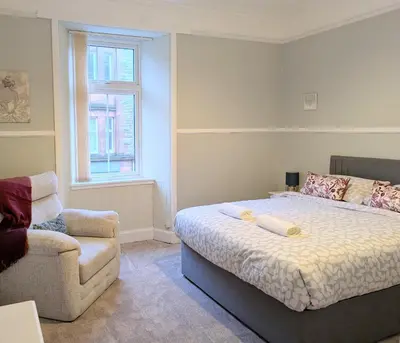 a bedroom with a bed and a couch and a chair at Longrow Apartment in Campbeltown