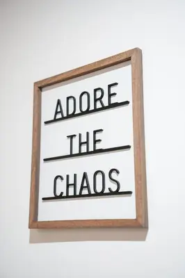 a framed sign with the words adore the chaos at The Lancefield Luxe in Glasgow