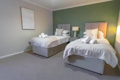 two beds in a room with green walls at Cruachan House in Falkirk