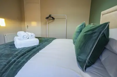 a bed with two towels and pillows on it at Cruachan House in Falkirk