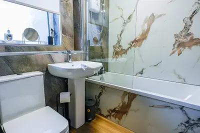 a bathroom with a sink and a toilet and a tub at Cruachan House in Falkirk