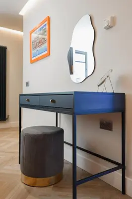 a blue desk with a mirror and a stool at Old Kirk Apartment in Oban