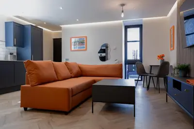 a living room with a couch and a kitchen at Old Kirk Apartment in Oban