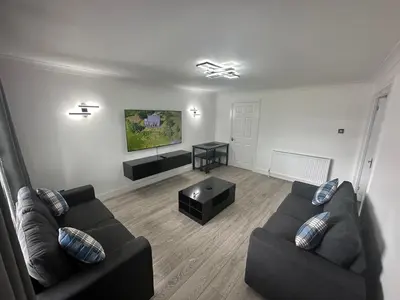 a living room with two couches and a table at Family - Garden - Parking - WiFi - Sleeps 5 in Tullibody