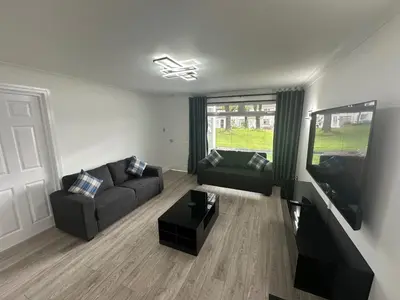 a living room with a couch and a flat screen tv at Family - Garden - Parking - WiFi - Sleeps 5 in Tullibody