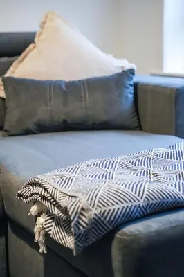 a blanket sitting on a couch with two pillows at Sedgebank House in Livingston