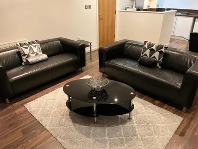 a living room with black leather couches and a coffee table at City centre luxury apartment in Glasgow