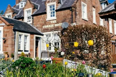 a house with a flower garden in front of it at The Corrie Hotel in Corrie