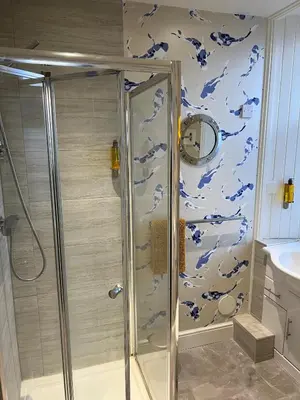 a bathroom with a shower with blue and white wallpaper at The Corrie Hotel in Corrie