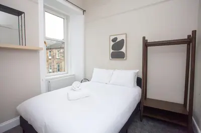 a bedroom with a white bed and a mirror at Stylish Southside 2 Bedroom Flat with Free Parking in Glasgow