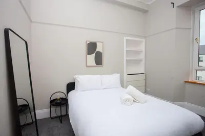 a bedroom with a large white bed and a window at Stylish Southside 2 Bedroom Flat with Free Parking in Glasgow