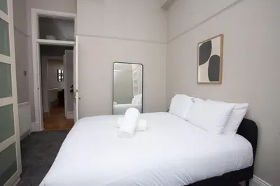 a bedroom with a large white bed with a mirror at Stylish Southside 2 Bedroom Flat with Free Parking in Glasgow