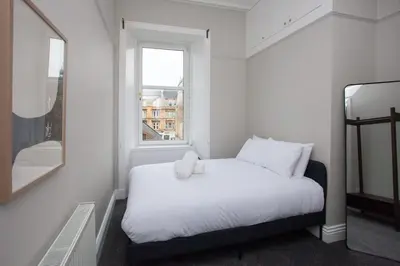 a bedroom with a white bed with a teddy bear on it at Stylish Southside 2 Bedroom Flat with Free Parking in Glasgow