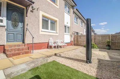 a house with a blue door and chairs in a yard at The Kings Height close to Glasgow and Edinburgh in Airdrie