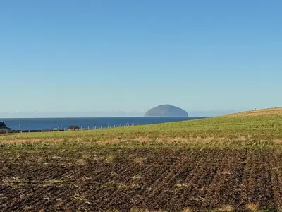 a field with the ocean in the background at Turnberry Holiday Park Amazing Sea View in Girvan