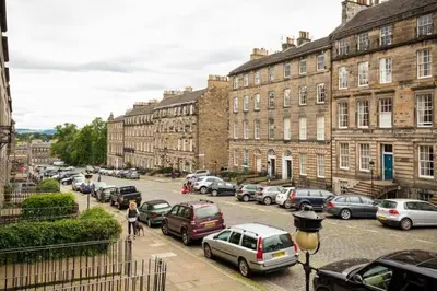 a city street with cars parked in front of buildings at Cozy 1 bed Garden flat in the New Town City Centre in Edinburgh