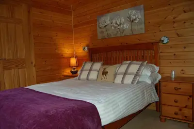 a bedroom with a bed in a log cabin at Woodland Oak Log Cabin, by Meall nan Tarmachan in Killin