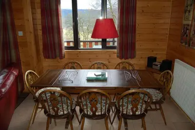 a dining room with a wooden table and chairs at Woodland Oak Log Cabin, by Meall nan Tarmachan in Killin