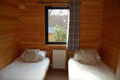 two beds in a log cabin with a window at Woodland Oak Log Cabin, by Meall nan Tarmachan in Killin