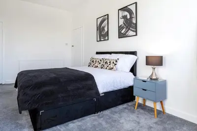 a bedroom with a bed and a lamp on a nightstand at Cosy 3 bed home in Cardonald G52 in Cardonald