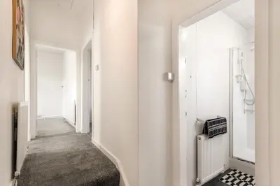 a hallway with white walls and an open door at Cosy 3 bed home in Cardonald G52 in Cardonald
