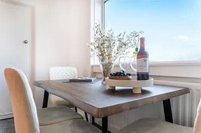 a dining room table with a bottle of wine and glasses at Cosy 3 bed home in Cardonald G52 in Cardonald