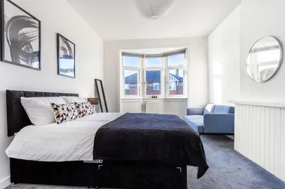 a bedroom with a large bed and a blue chair at Cosy 3 bed home in Cardonald G52 in Cardonald