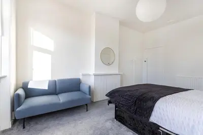 a bedroom with a bed and a blue couch at Cosy 3 bed home in Cardonald G52 in Cardonald